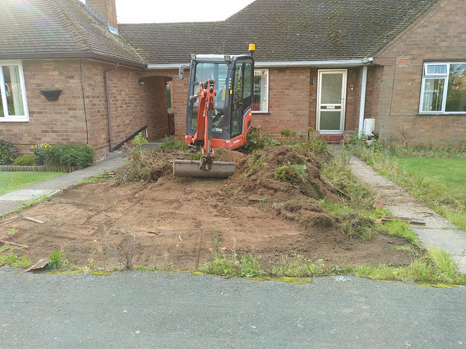 Mini digger removing top soil from garden