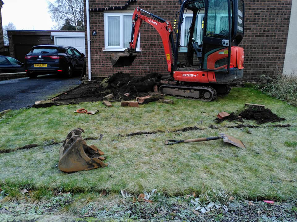 Mini digger laying grass in garden