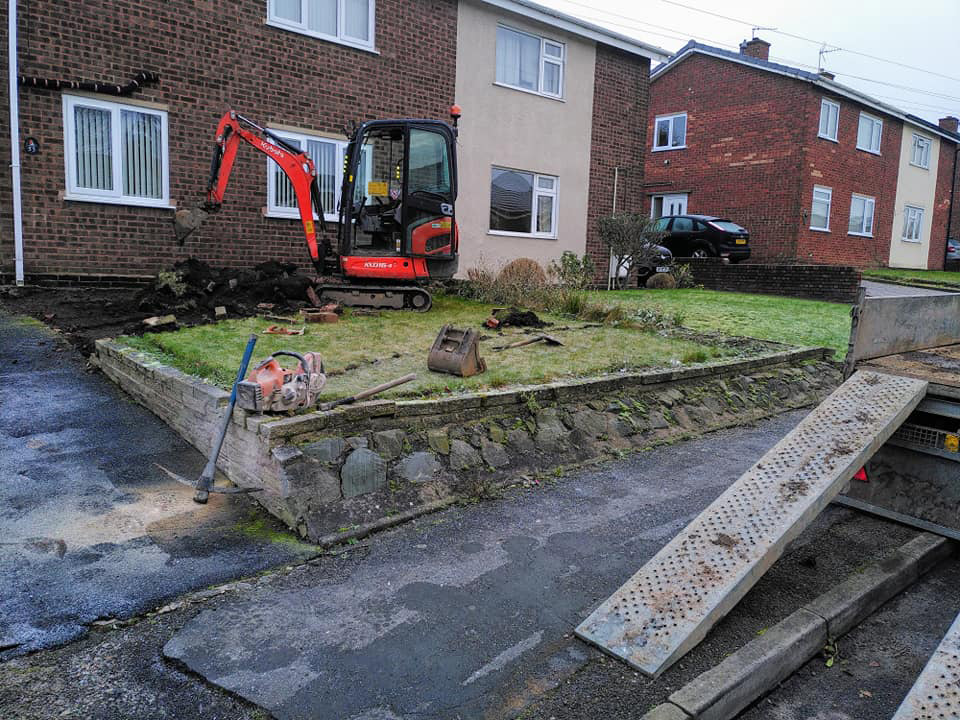 Mini digger excavating soil from garden