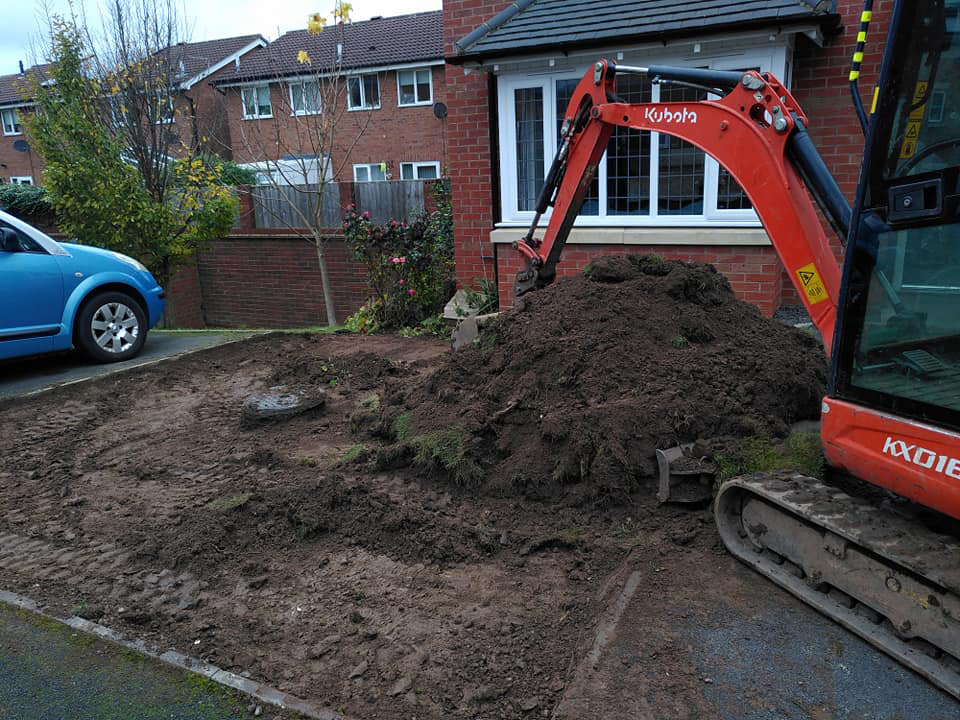 Mini digger removing top soil from garden