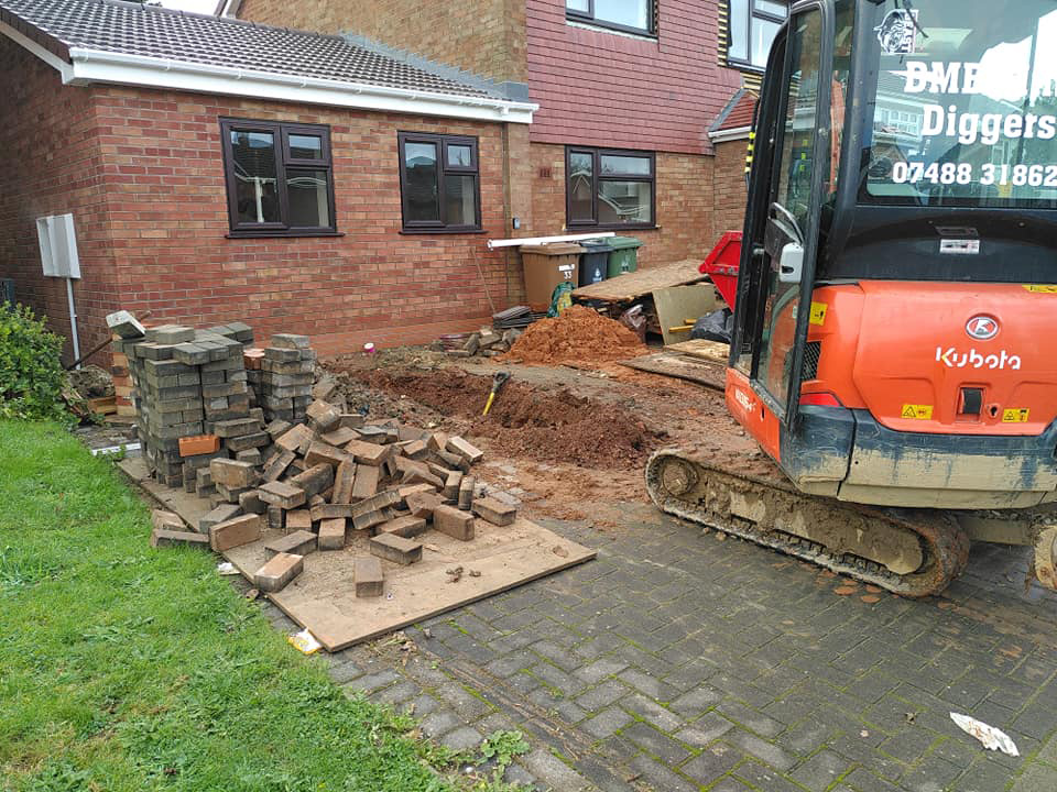 Mini digger excavating ditch in garden