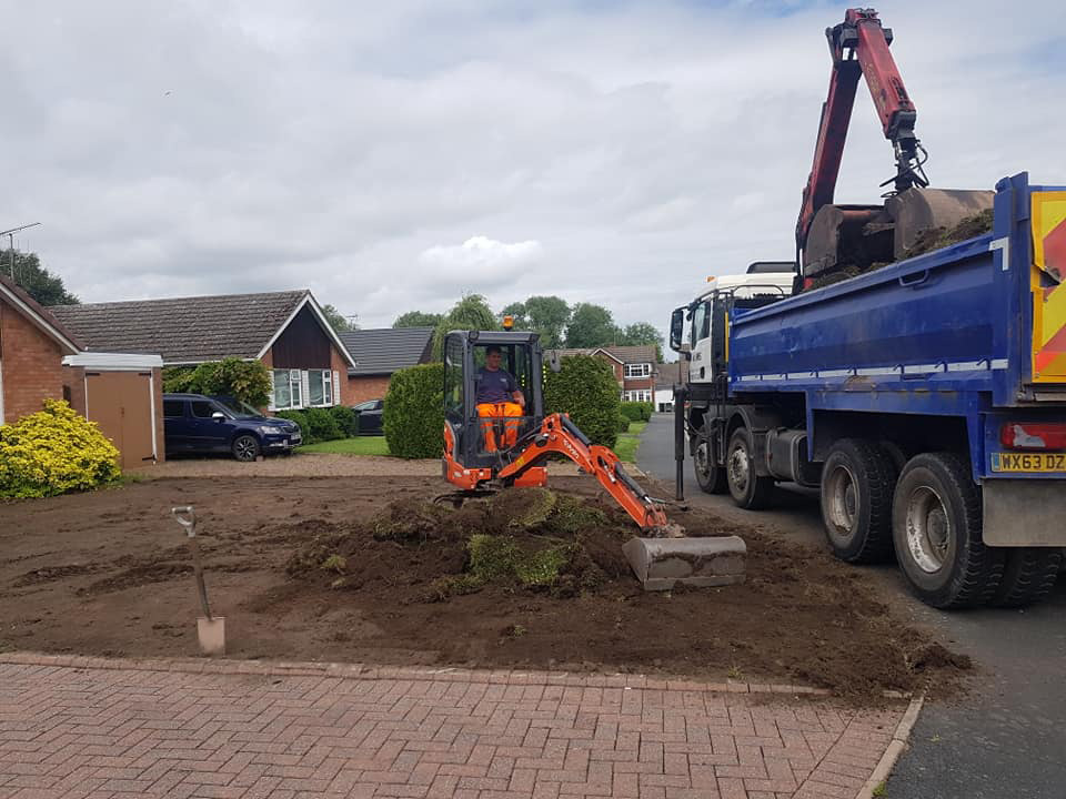 mini digger removing top soil on garden